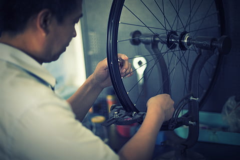 ambachtsman, ernstig, tafel, bezetting, een persoon, vervoer, repareren, wijze van transport, wiel, werkend, binnenshuis, volwassen, band, mannen, bekwaamheid, fiets, pedaal, gereedschap, monteur, hoofdschot, concentratie, profielweergave, spaak, Lab jas, 5K, CC0, publiek domein, royaltyvrij