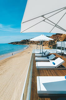 empty beach beds, human, person, building, water, outdoors, shoreline, sea, nature, ocean, wood, housing, canopy, coast, beach, balcony, boardwalk, bridge, porch, hardwood, awning, sky, land, day, scenics - nature, chair, beauty in nature, no people, sunlight, tranquil scene, horizon, tranquility, parasol, horizon over water, mountain, table, luxury, 4K, CC0, public domain, royalty free